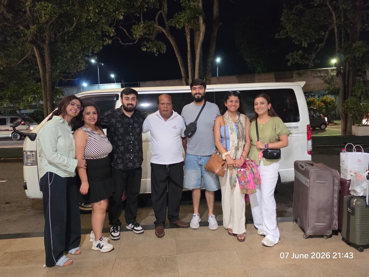 Group of friends with their guide and tour van at the airport